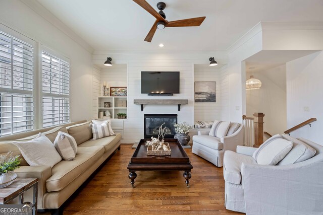 living room with a large fireplace, wood finished floors, a ceiling fan, and ornamental molding