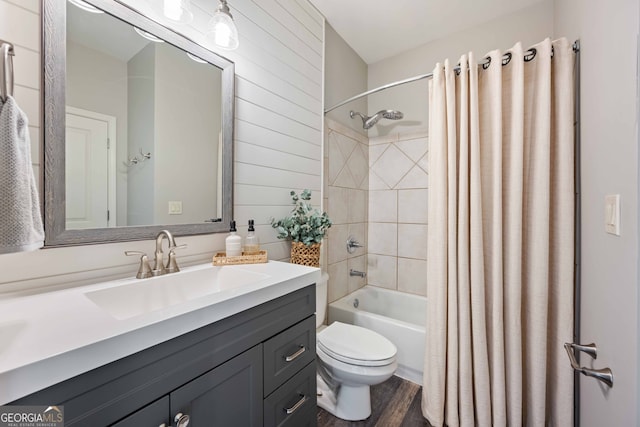 full bathroom with vanity, wooden walls, wood finished floors, shower / bath combo with shower curtain, and toilet