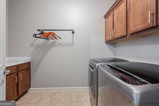 laundry area featuring baseboards, cabinet space, washing machine and dryer, and light tile patterned flooring