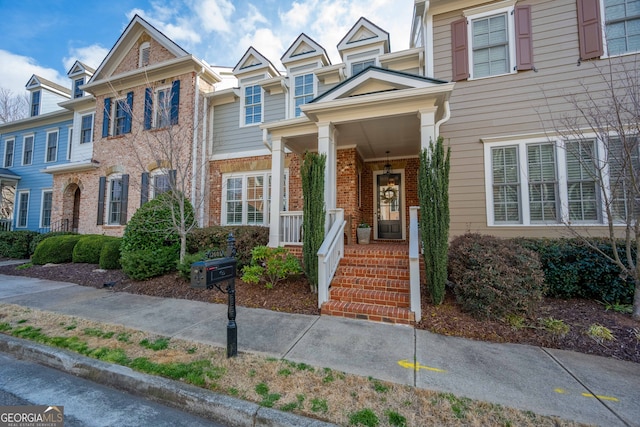 multi unit property featuring a porch and brick siding