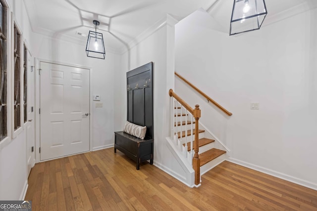 foyer with stairs, baseboards, ornamental molding, and wood finished floors