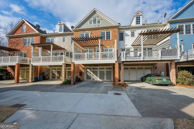 view of front of home with brick siding, a garage, driveway, and a pergola