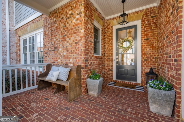 view of exterior entry with brick siding and covered porch