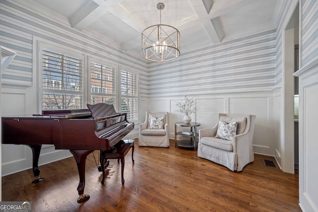 living area featuring a decorative wall, visible vents, a notable chandelier, and coffered ceiling