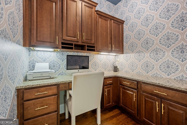 home office featuring built in study area, dark wood finished floors, and wallpapered walls