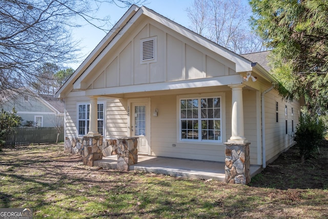 view of front of home with board and batten siding, stone siding, fence, and a shingled roof