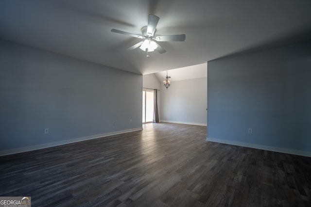 unfurnished room featuring lofted ceiling, ceiling fan with notable chandelier, dark wood finished floors, and baseboards