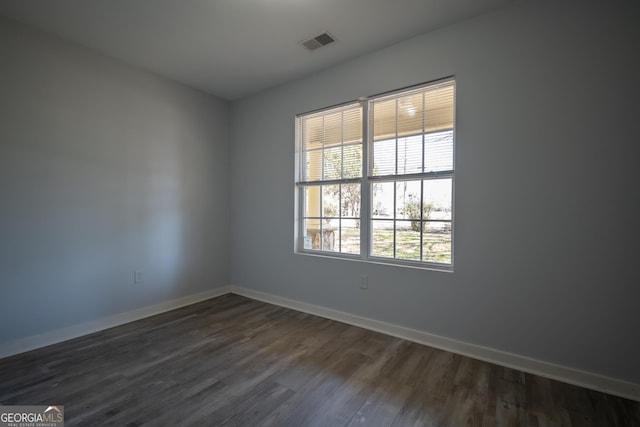 spare room with baseboards, visible vents, and dark wood finished floors