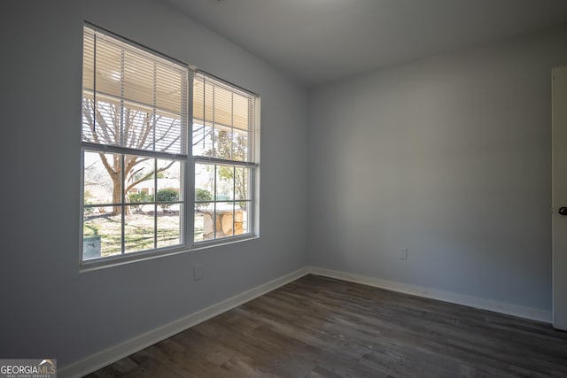 empty room featuring baseboards and dark wood finished floors