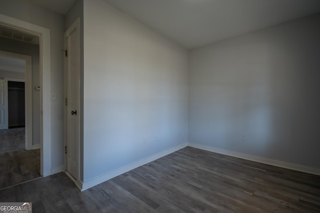 unfurnished room with visible vents, baseboards, and dark wood-type flooring