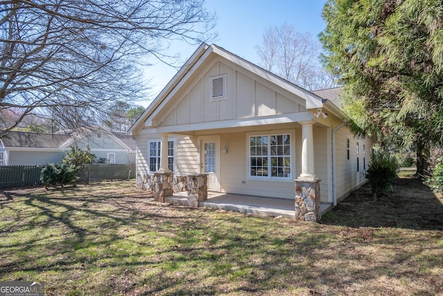 view of front of house featuring board and batten siding, a front yard, and fence