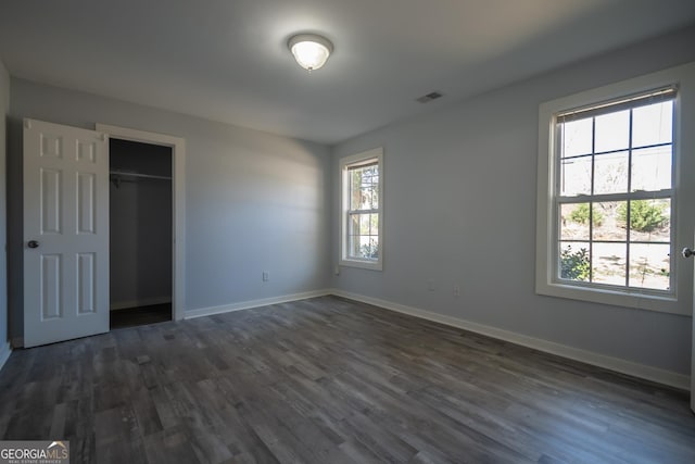 unfurnished bedroom featuring a closet, dark wood-style flooring, visible vents, and baseboards