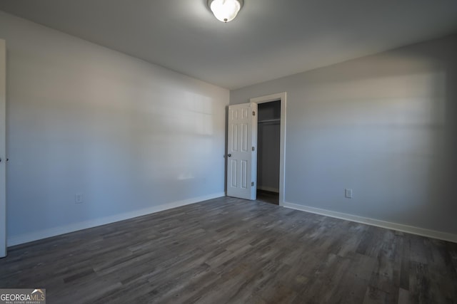 unfurnished room featuring baseboards and dark wood-style flooring