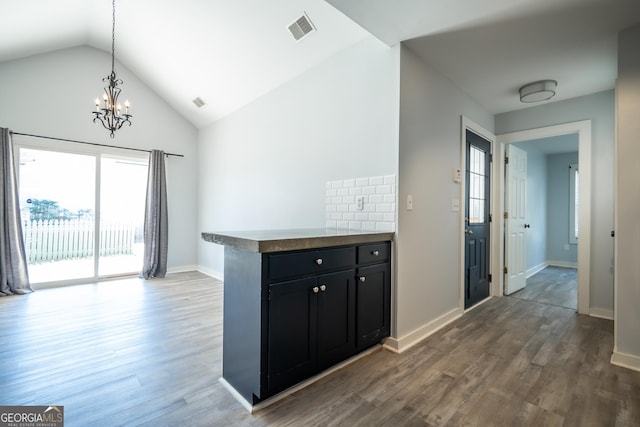 kitchen featuring dark cabinets, visible vents, vaulted ceiling, and wood finished floors