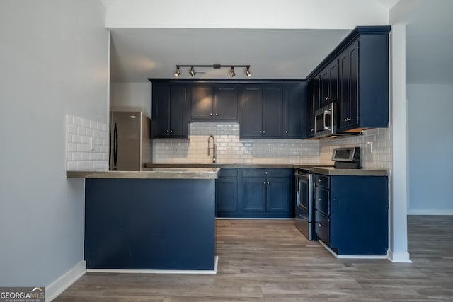 kitchen with a peninsula, light wood finished floors, stainless steel appliances, and backsplash