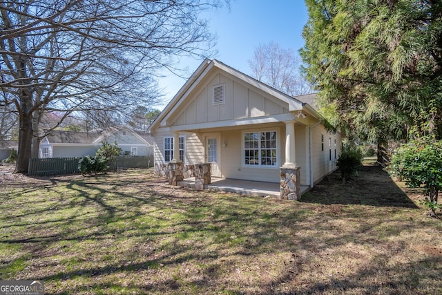 view of front facade with board and batten siding, a front yard, and fence