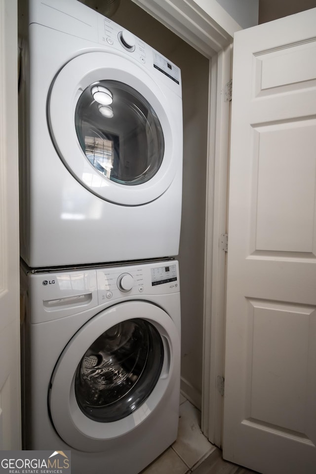 laundry area featuring stacked washer and dryer, light tile patterned floors, and laundry area