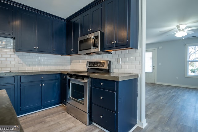 kitchen featuring stainless steel appliances, blue cabinets, light wood-style floors, and tasteful backsplash