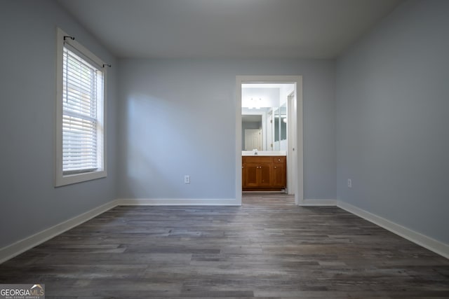 interior space featuring a sink, dark wood-style flooring, ensuite bath, and baseboards