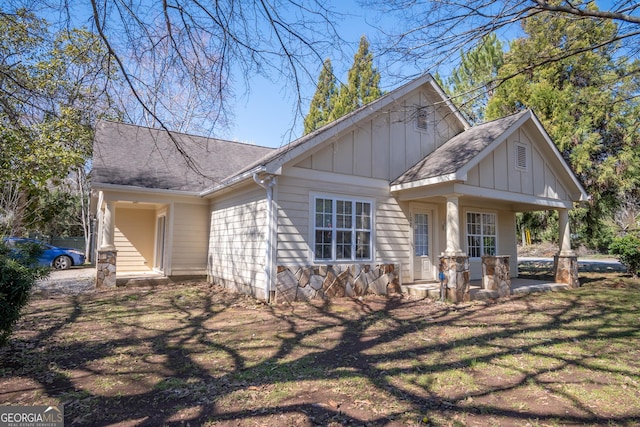 view of front of house featuring a front lawn, board and batten siding, and a shingled roof