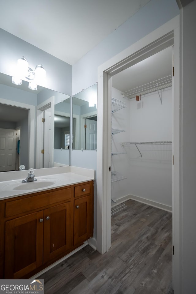 bathroom featuring wood finished floors, vanity, and a walk in closet