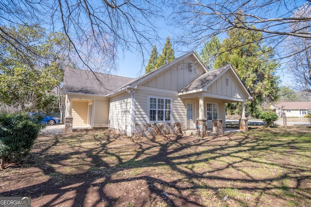 view of front of home with roof with shingles, board and batten siding, and a front yard