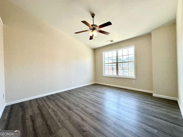 spare room with a ceiling fan, dark wood finished floors, visible vents, and baseboards