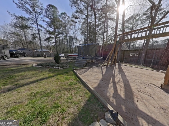 view of yard with a trampoline and fence