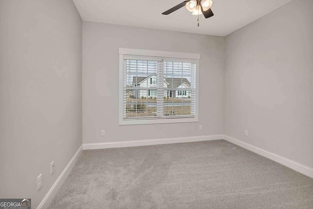 empty room with carpet floors, baseboards, and a ceiling fan