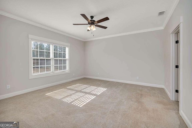 carpeted empty room featuring baseboards, visible vents, a ceiling fan, and crown molding