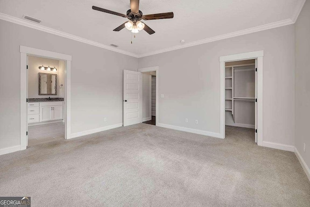 unfurnished bedroom featuring carpet flooring, visible vents, baseboards, a spacious closet, and crown molding