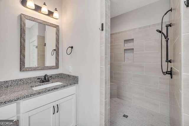 bathroom featuring tiled shower and vanity