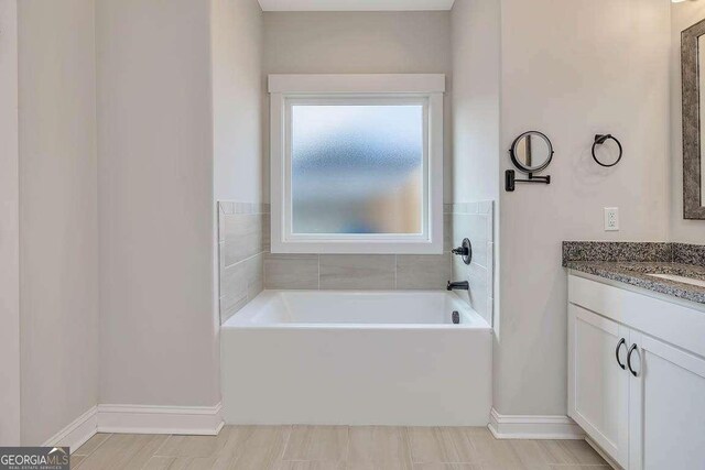 bathroom featuring a garden tub, vanity, and baseboards