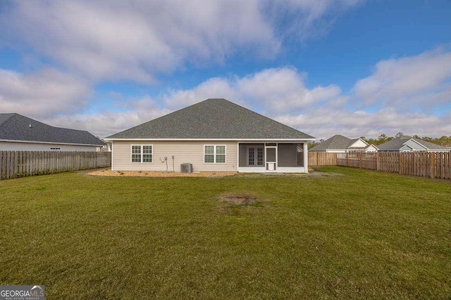 back of property with a sunroom, a fenced backyard, a yard, and central AC unit