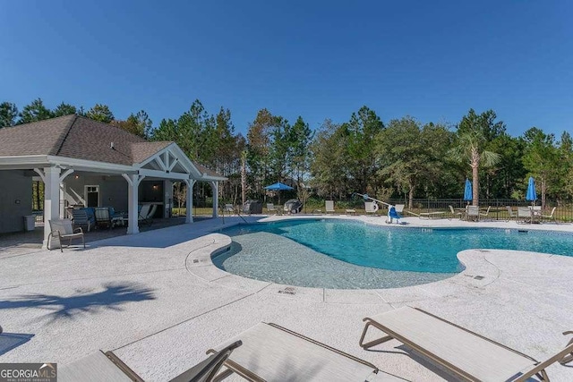 community pool with a patio area and fence