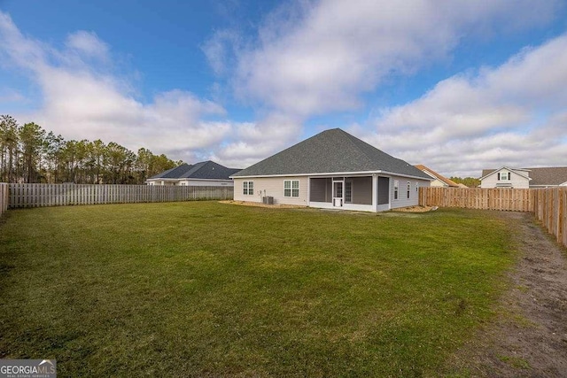 back of house with a fenced backyard and a yard