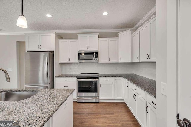 kitchen featuring stainless steel appliances, dark wood-style flooring, a sink, white cabinets, and crown molding