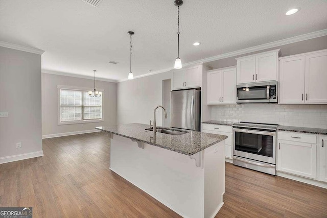 kitchen with wood finished floors, appliances with stainless steel finishes, a sink, and decorative backsplash