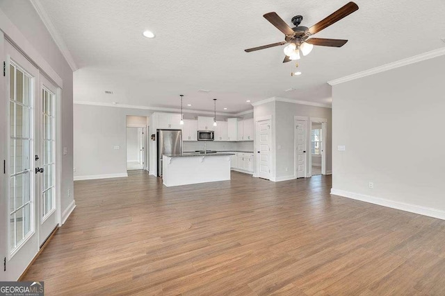 unfurnished living room with a textured ceiling, wood finished floors, and baseboards