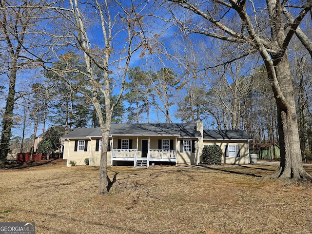 ranch-style home featuring covered porch, a chimney, and a front lawn