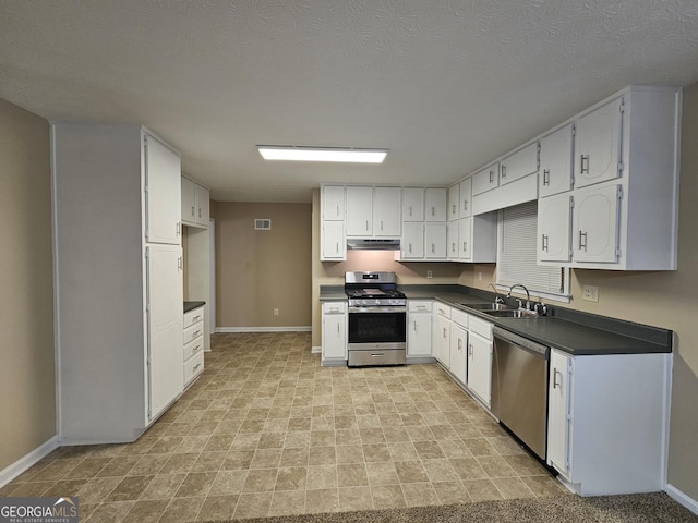 kitchen featuring under cabinet range hood, stainless steel appliances, a sink, visible vents, and dark countertops