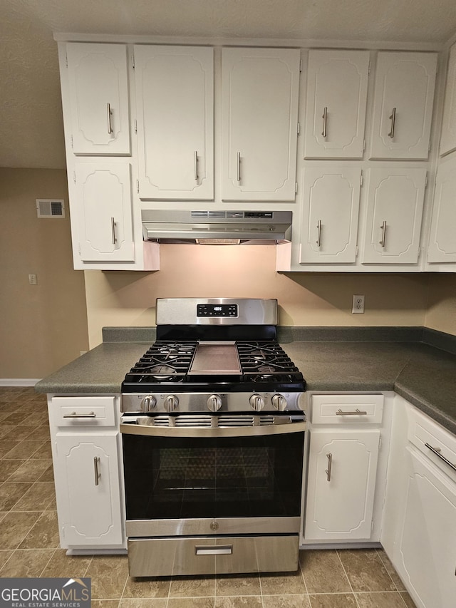 kitchen with dark countertops, under cabinet range hood, and gas range