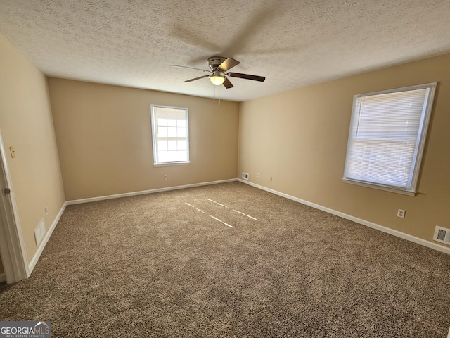 carpeted empty room featuring a ceiling fan, visible vents, and baseboards