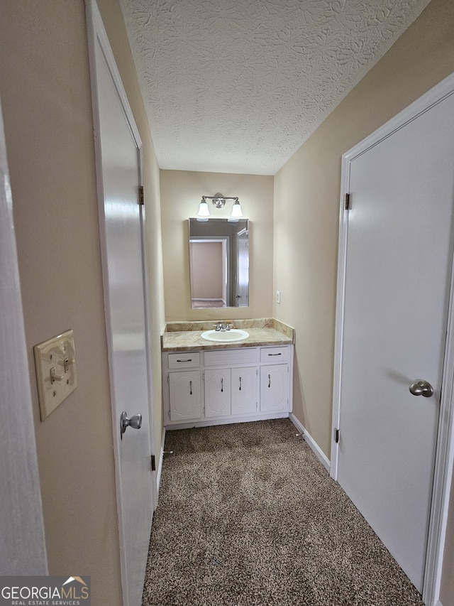 bathroom with baseboards, vanity, and a textured ceiling