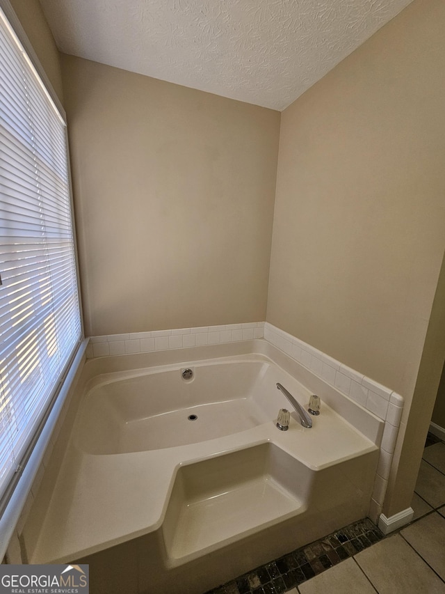 full bathroom featuring a textured ceiling, tile patterned flooring, and a garden tub