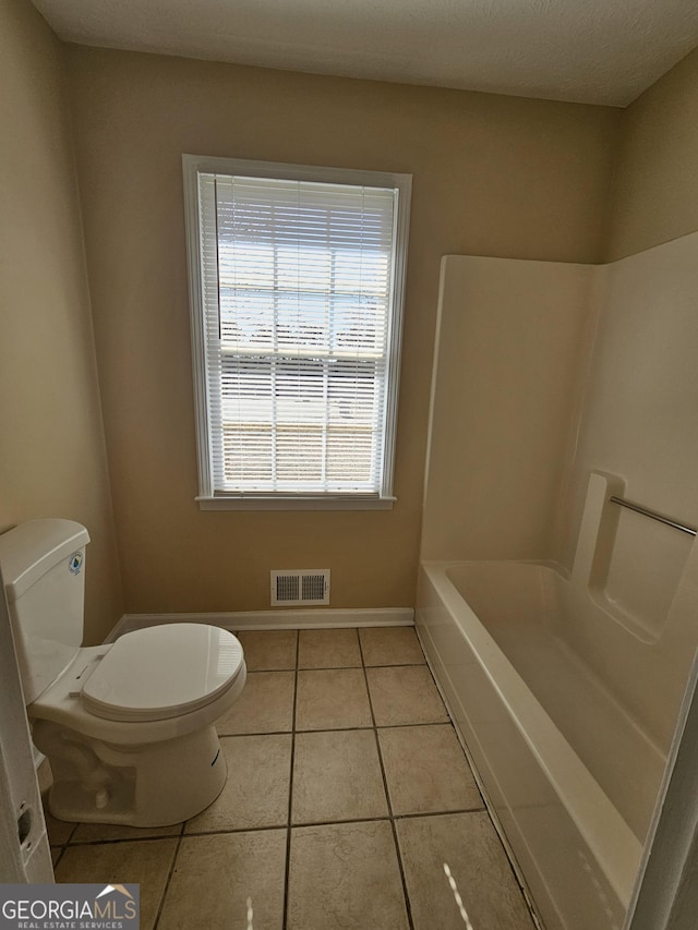 full bathroom with toilet, a washtub, visible vents, baseboards, and tile patterned floors