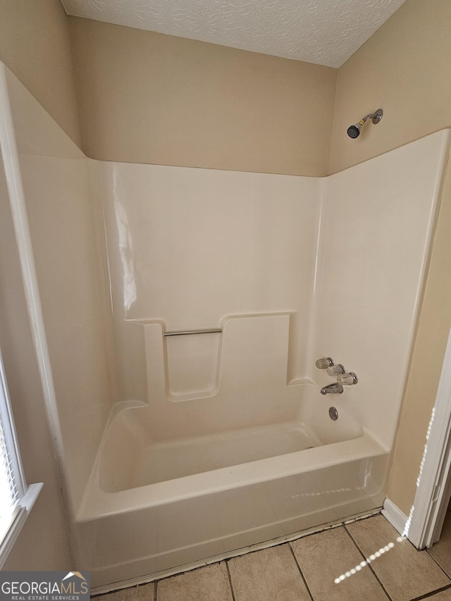 bathroom with tile patterned flooring, washtub / shower combination, and a textured ceiling