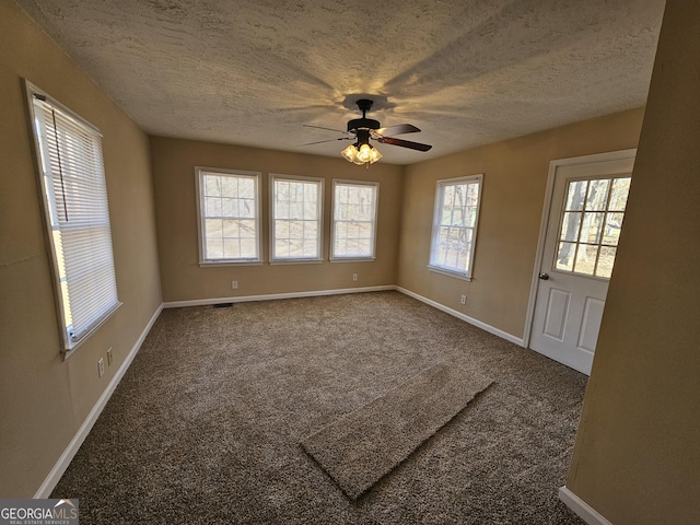 carpeted empty room featuring ceiling fan, baseboards, and a textured ceiling