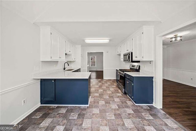 kitchen with light countertops, appliances with stainless steel finishes, white cabinetry, a sink, and blue cabinets