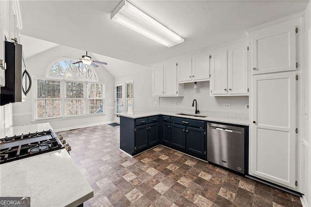 kitchen with blue cabinetry, appliances with stainless steel finishes, white cabinets, a sink, and a peninsula